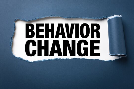Behavior change phrase written on white paper under torn dark blue background