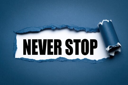 Never stop concept written under torn blue paper