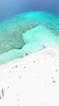 Aerial drone view of white sand beach with turquoise water and Camiguin volcano island in the background Philippines