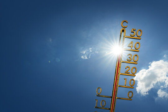 Blue sky on a hot summer day with sun and a thermometer. Extremely hot weather forecast.