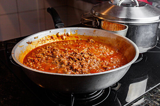 Bolognese meat sauce simmering in frying pan on stove