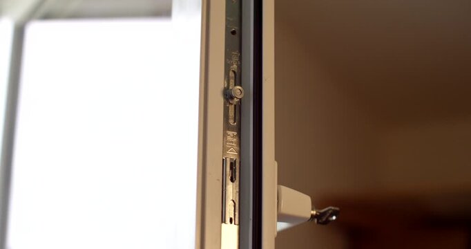 Close-up view of locking hardware mechanism installed inside a white window frame profile