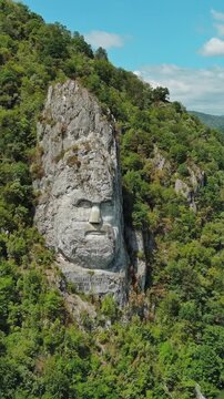 Aerial view of stone carved statue portrait of ancient dacian king Decebal. Sculpture near Danube River, Romania. Vertical video 4k