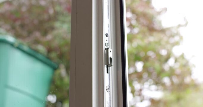 Close-up shot of the metallic locking mechanism on an open white plastic window frame