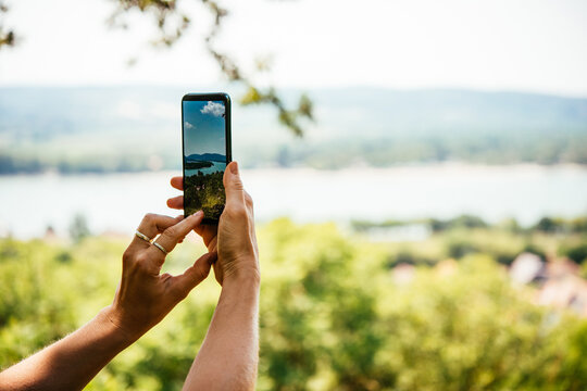 A person takes a mobile photo of a landscape while travelling.