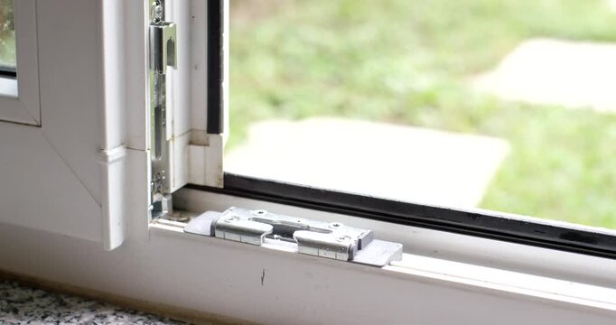 Close-up view of the locking hardware and base track of an open white plastic window