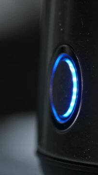Vertical video: Pressing fingertip on button at counter, lighting blue LED ring powering device