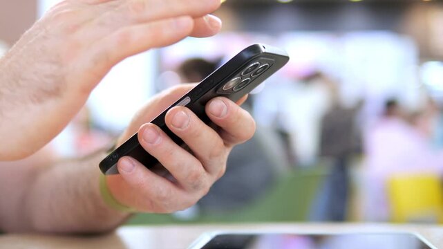 Close-up of hand typing on smartphone. Blurred background suggests public setting. Focused fingers show intent or urgency. Suitable for tech, communication, or daily life themes