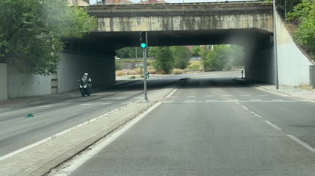 MADRID, SPAIN - June 24, 2026: Vehicle travels through an urban underpass while a municipal waste collection truck and other traffic move nearby. Urban transportation infrastructure in a Madrid city d