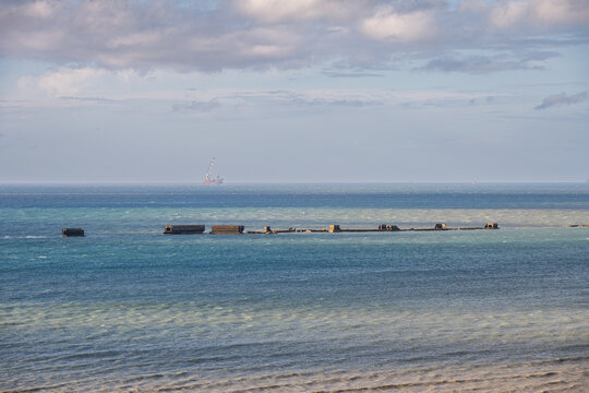 Arromanches les Bains, France - June 2, 2026: Historic concrete blocks and remains of the WWII artificial Mulberry Harbor visible in the blue sea water off the coast of Arromanches les Bains in Norman