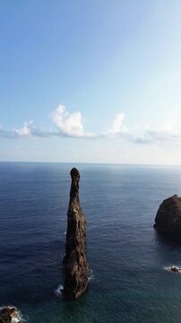 Aerial drone view of dramatic volcanic rock formation Ilheus da Ribeira da Janela rising from the ocean in Madeira Portugal