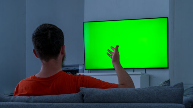 Man watching blank green tv screen at home