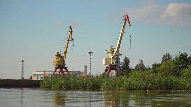 Abandoned shipyard with old rusty cranes near the sea.