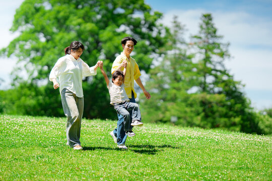 手を繋いで公園を歩く三人家族