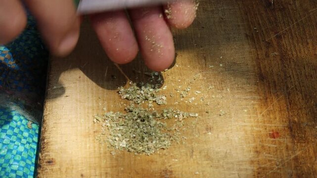 Marrakesh, Morocco - 20 June 2026: Hands chopping dried cannabis with a knife on a wooden board