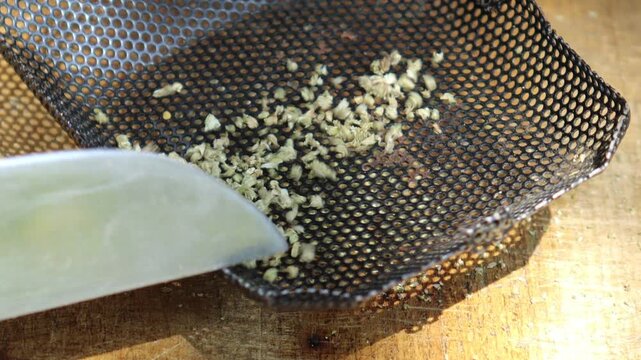 Marrakesh, Morocco - 20 June 2026: Hands chopping dried cannabis with a knife on a wooden board