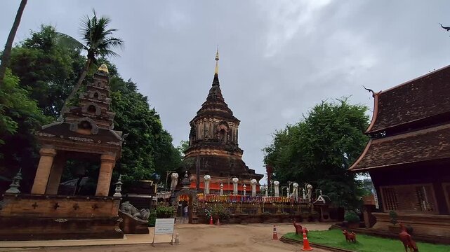 Ancient brick chedi at Wat Lok Moli temple in Chiang Mai, Thailand, adorned with colorful traditional Lanna Tung flags, showcasing rich cultural heritage.