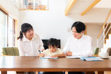 Fototapeta premium 勉強する小学一年生の男の子と教える両親