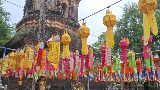 Ancient brick chedi at Wat Lok Moli temple in Chiang Mai, Thailand, adorned with colorful traditional Lanna Tung flags, showcasing rich cultural heritage.