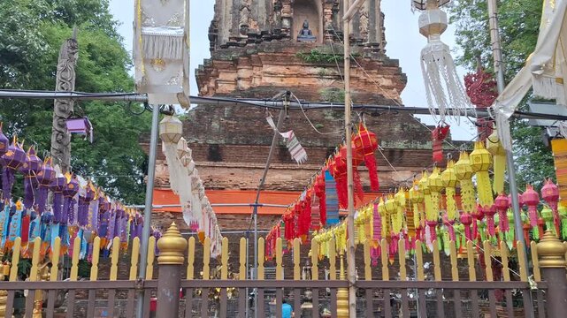 Ancient brick chedi at Wat Lok Moli temple in Chiang Mai, Thailand, adorned with colorful traditional Lanna Tung flags, showcasing rich cultural heritage.