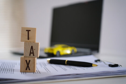 Car tax concept. close up tax wooden text with a toy car. saving money for transport. Toy car and Wooden blocks with the word TAX . The concept for paying TAX for car in future
