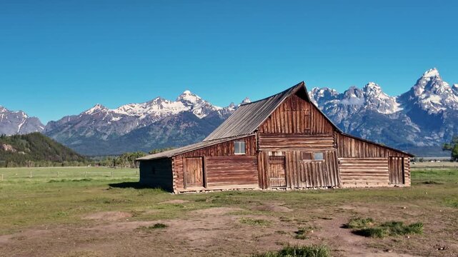 Iconic T.A. Moulton Barn standing before dramatic snowcapped Teton peaks under a clear blue sky
