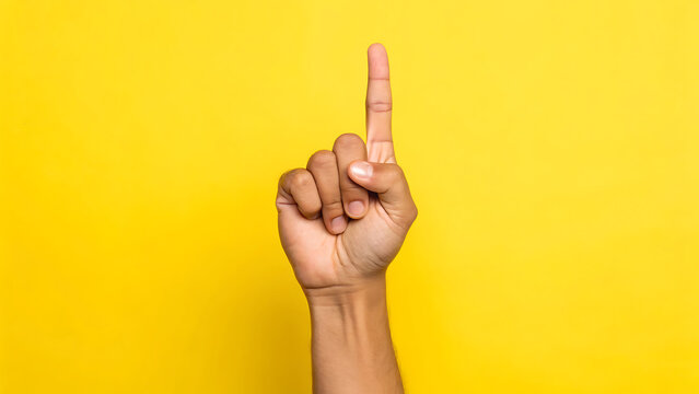 Human hand with index finger pointing upwards against a vibrant yellow background, showing a gesture of counting one or indicating a direction