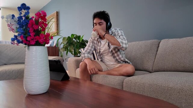 Young man drinking milk while using tablet