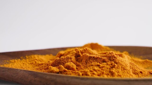 Turmeric powder pouring into wooden bowl. Aromatic spice and cooking ingredient concept. High quality 4k footage