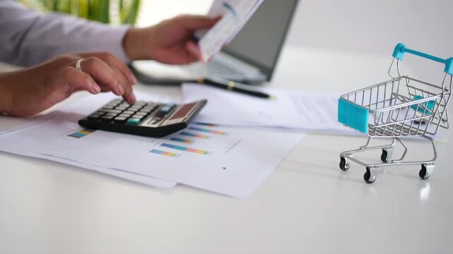 A male accountant holds an invoice and calculates with a calculator. He analyzes expenses, bills, and finances at his desk.
