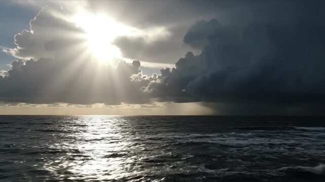 Dramatic sunbeams pierce through stormy clouds over a vast, shimmering ocean.
