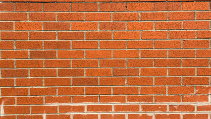 Fototapeta premium Brick wall with uniform pattern in bright red color on a sunny day