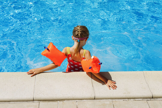 Pool vacation in summer by the sea -  Child in swimming pool on ring toy. Kids swim.