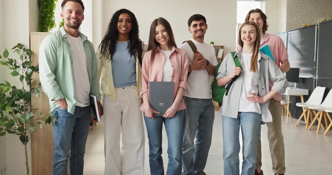 Students group in classroom smiling for education. Young adults with backpacks in a university campus interior, showing learning and teamwork. Teamwork and student success education concept.