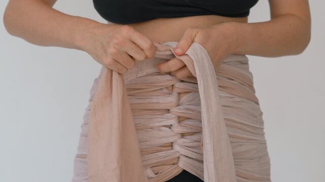 Close view of bengkung belly wrap on postpartum woman. Slow motion.