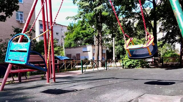 Empty swings in playground outdoors, childhood recreation area, community leisure space, family friendly environment.