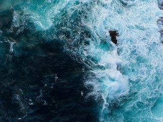 Obraz premium Aerial view of turbulent ocean waves with foamy surf