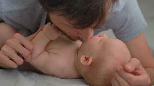 Father kissing baby son's cheek and chest. Very close-up. Slow motion.