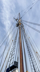 Obraz premium Tall ship mast with rigging reaching toward blue sky