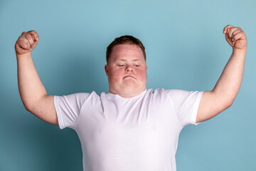 Fototapeta premium Person in a white shirt flexing muscles against a blue background.