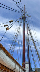 Fototapeta premium Masts and rigging of a tall ship against a blue sky in a harbor setting