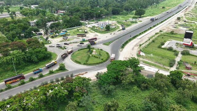 Aerial View of a Curving Highway Intersection with Vehicles and Greenery Around Parks and Small Buildings