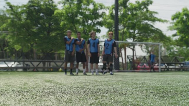 Soccer ball on green artificial turf pitch with blurred players background, football match training session concept before kickoff at sports stadium