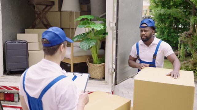 Home moving and delivery service concept. Teamwork of professional home and furniture moving with a truck from business service company. Two male movers in uniforms working and delivering to customer.