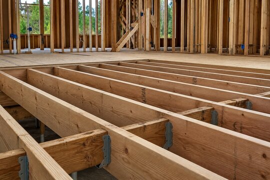 Exposed wooden joists supporting an unfinished floor on a construction site.