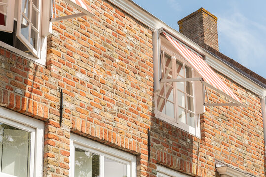 Middelburg, Netherlands. Close-up of traditional Dutch brick facade with striped awning and open window detail