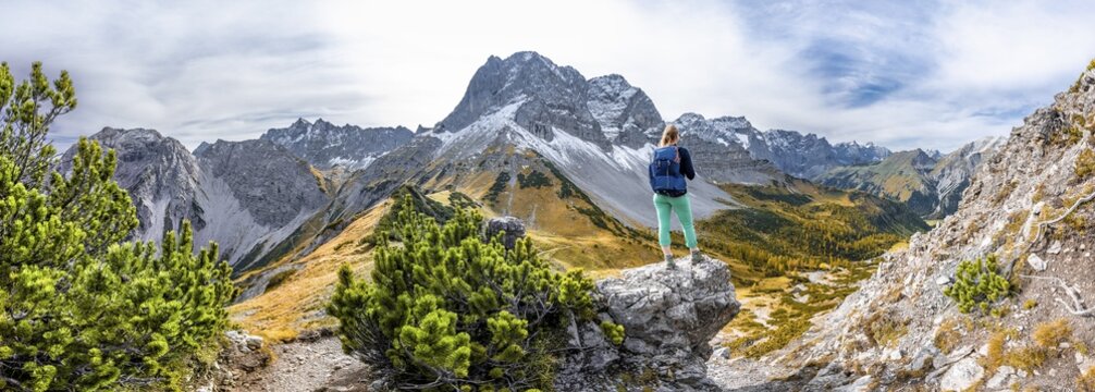 Hiker on a rock, autumnal trees, hiking to Hahnkampl, on the left summit of Lamsenspitze, Eng, community Hinterri&szlig;, Karwendel Mountains, Alpenpark Karwendel, Tyrol, Austria