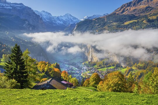 View from the village of the Lauterbrunnen Valley with Staubbach waterfall in autumn with morning fog, Wengen, Bernese Oberland, Canton of Bern, Switzerland