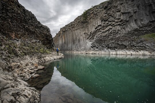 Tourist standing by the river in Stu&eth;lagil Canyon, turquoise blue river between basalt columns, Egilsstadir, Iceland