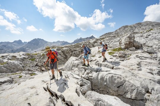 Three hikers in a landscape of washed-out karst rocks, Funtenseetauern, Steinernes Meer, Berchtesgaden National Park, Berchtesgadener Land, Upper Bavaria, Bavaria, Germany